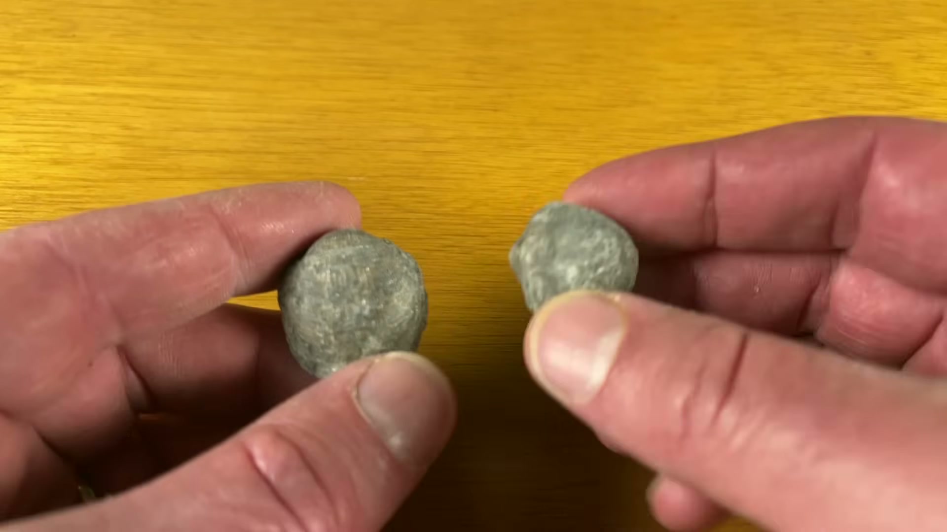 Comparing two rounded stones to check hardness and suitability for rock tumbling