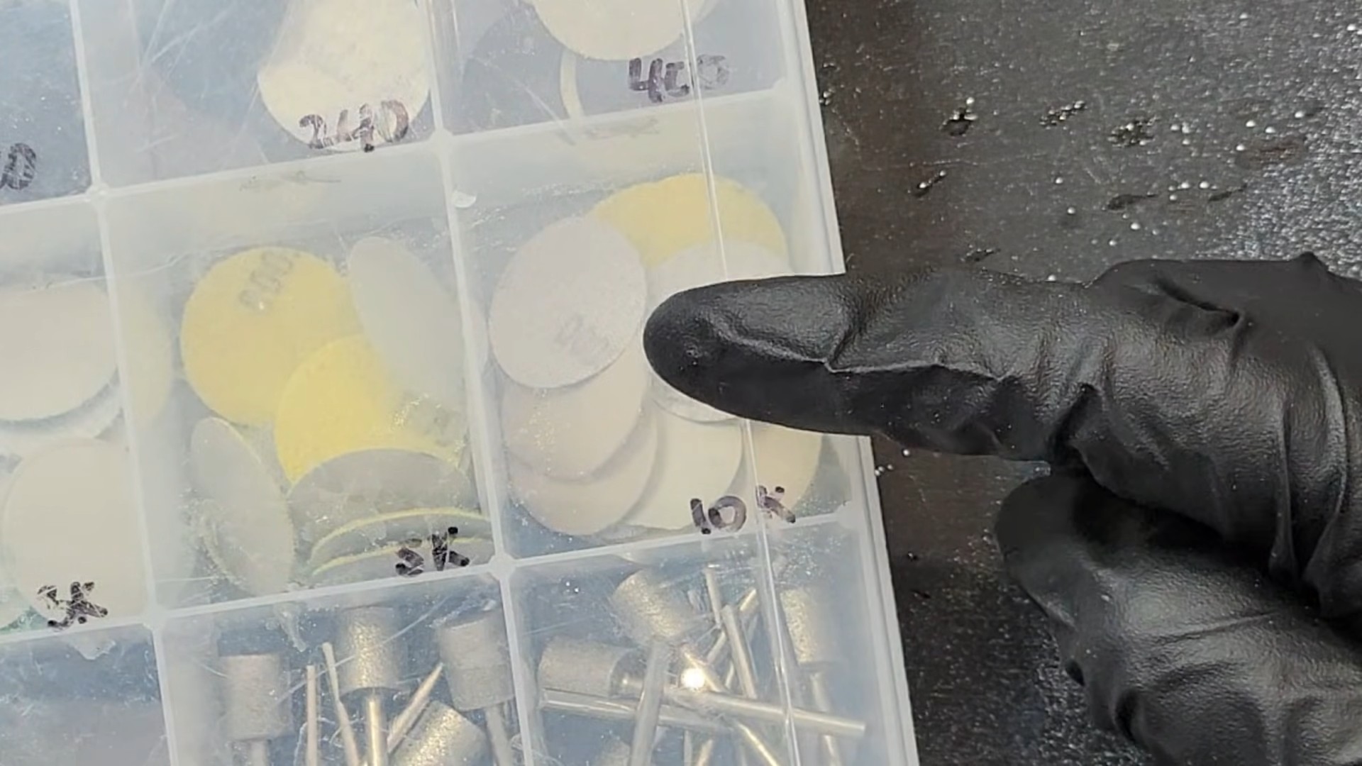 Organized accessory case showing sanding discs labeled by grit (240, 400, 800, 3K, 10K) and felt polishing wheels used for the final polish stage