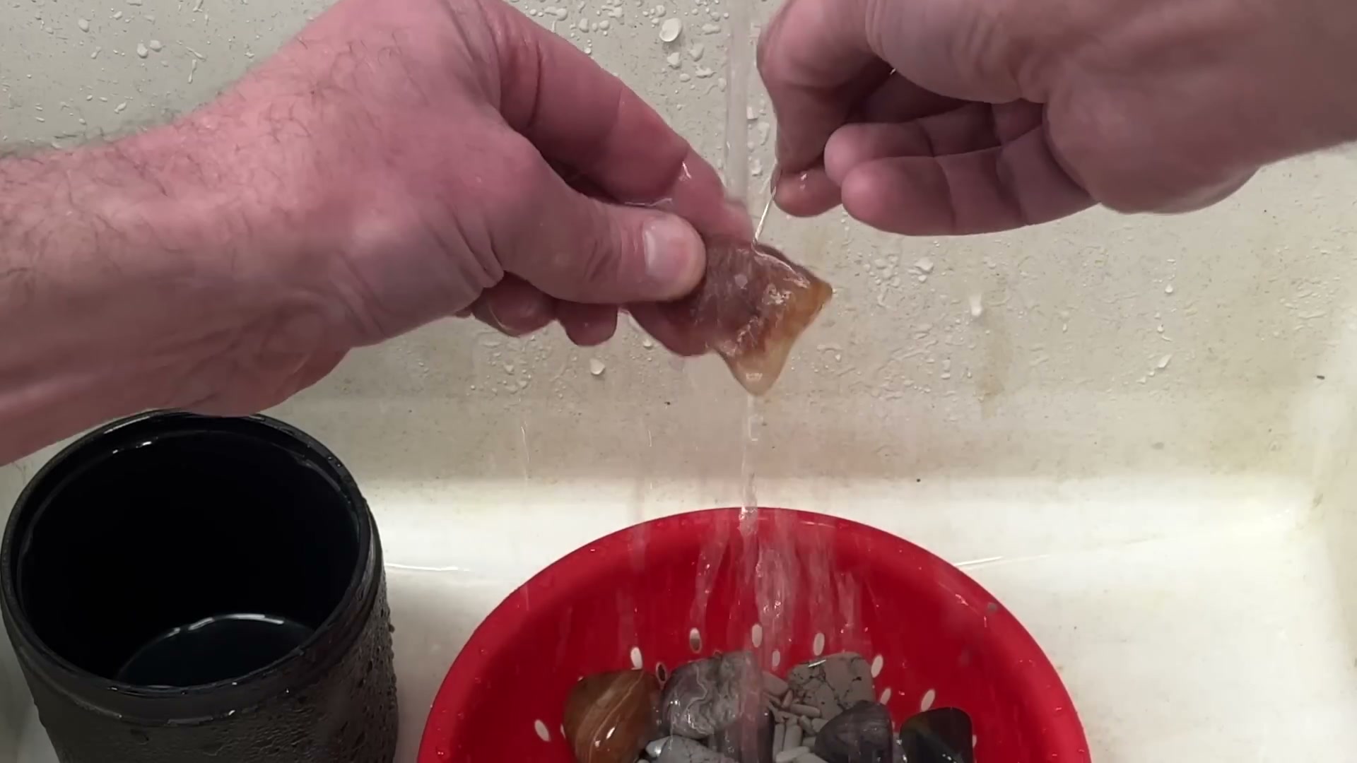 rinsing tumbled rocks in colander between grit stages