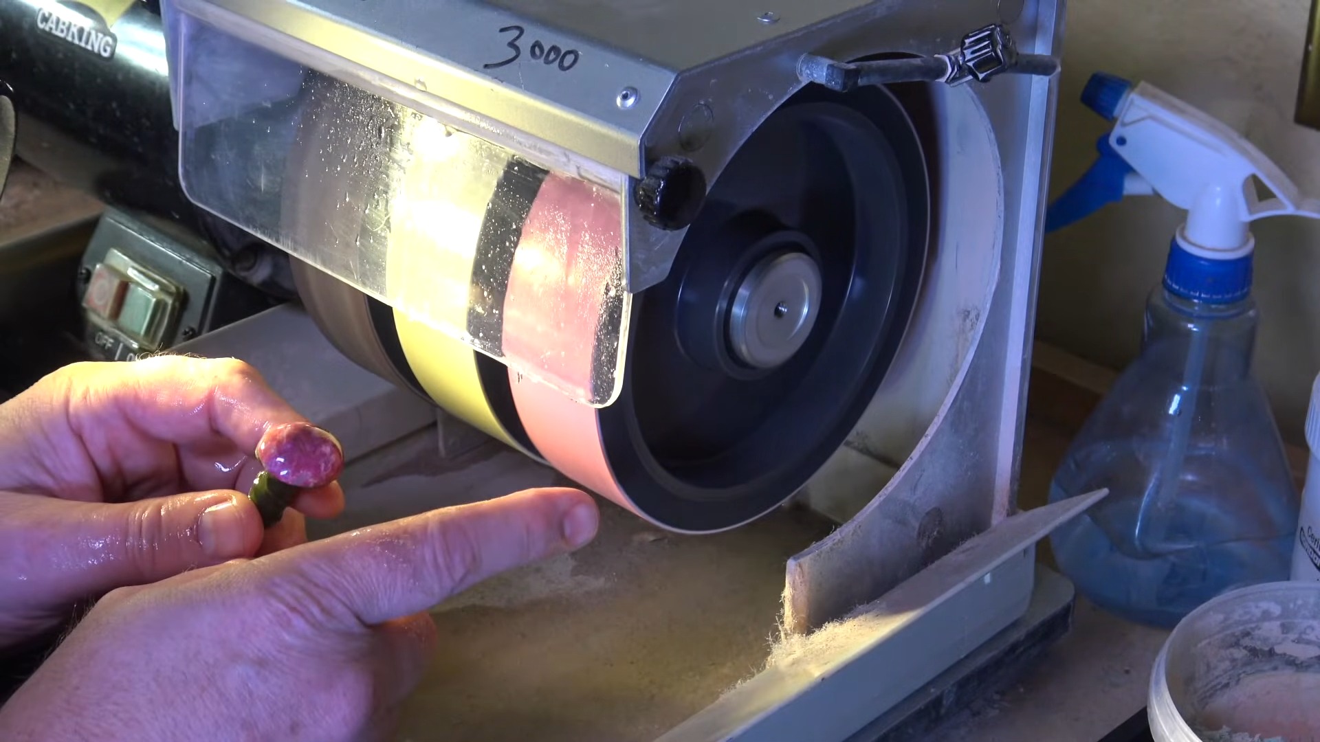 Hand pressing dopped cabochon against CabKing grit wheel