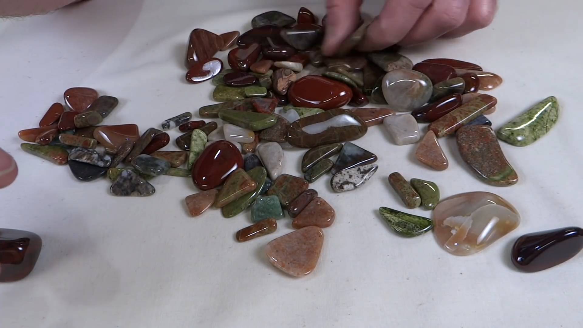 Assortment of polished tumbled stones on cream cloth