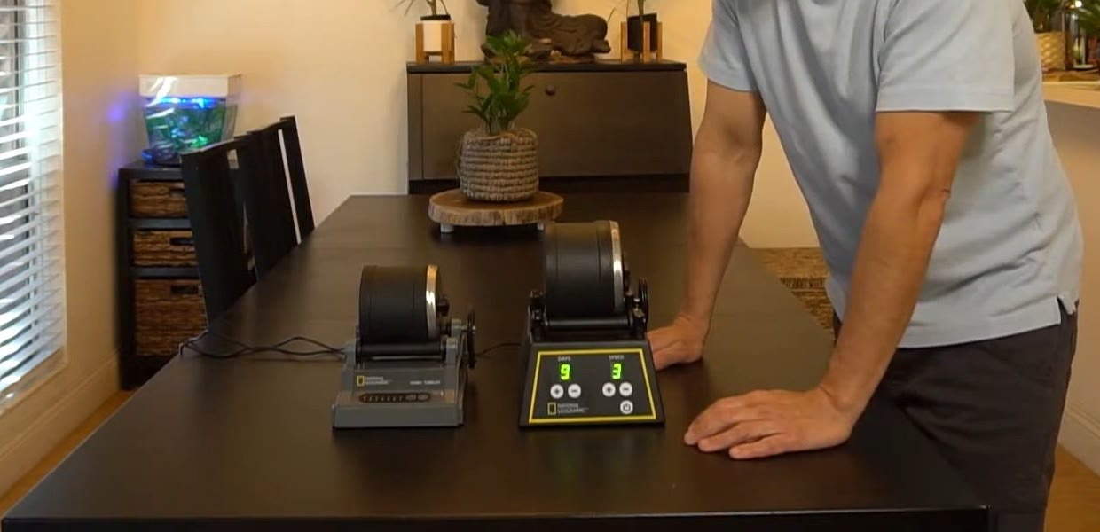 National Geographic Hobby Rock Tumbler and Professional Rock Tumbler side by side on a dining table, with the Professional's digital panel set to 9 DAYS at SPEED 3