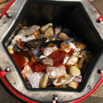 Tumbled agates and jasper glistening in an open rock tumbler barrel